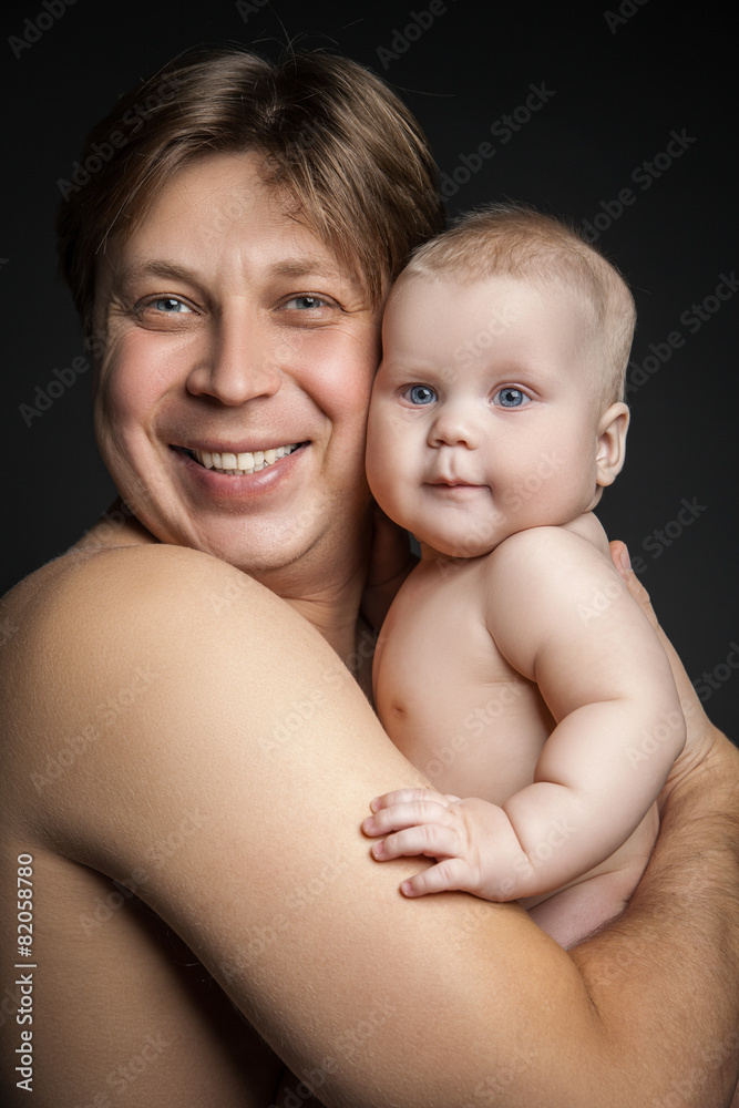 Father holding toddler son both looking at the camera. Father holding toddler son both looking at the camera.