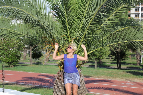 Happy woman in sunglasses posing near a palm