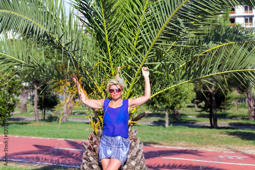 Happy woman in sunglasses posing near a palm