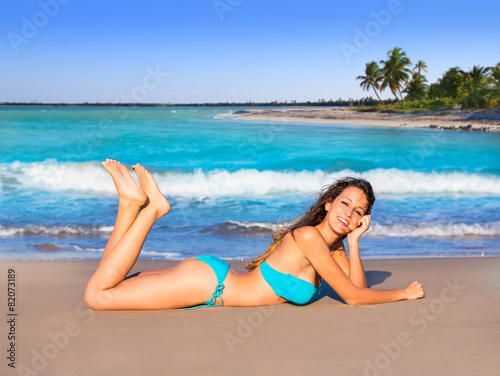 Brunette tourist lying in beach sand tanning happy