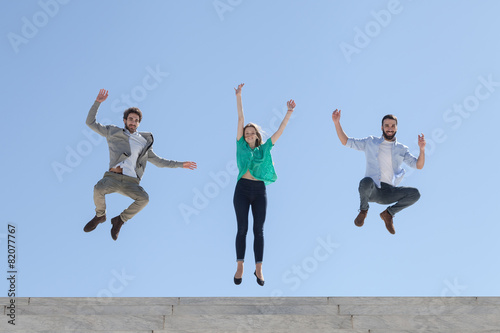 Three friends jump on top of a staircase