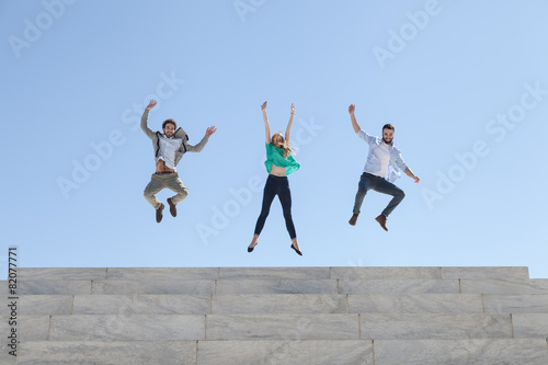 Three friends jump on top of a staircase