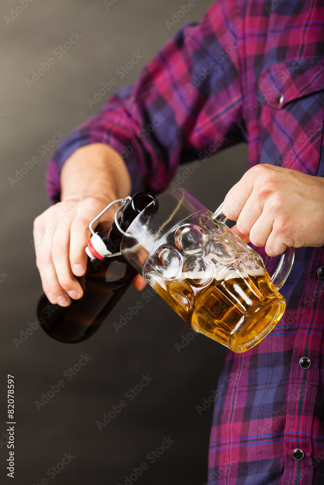 young man pouring beer from bottle into mug