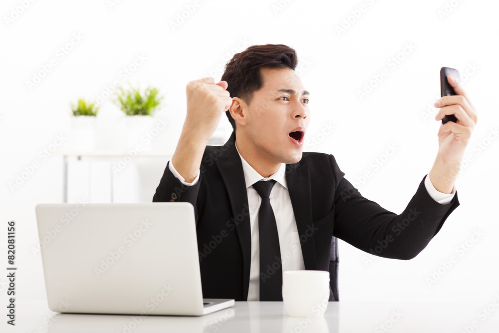 happy businessman watching the smart phone in office happy businessman watching the smart phone in office