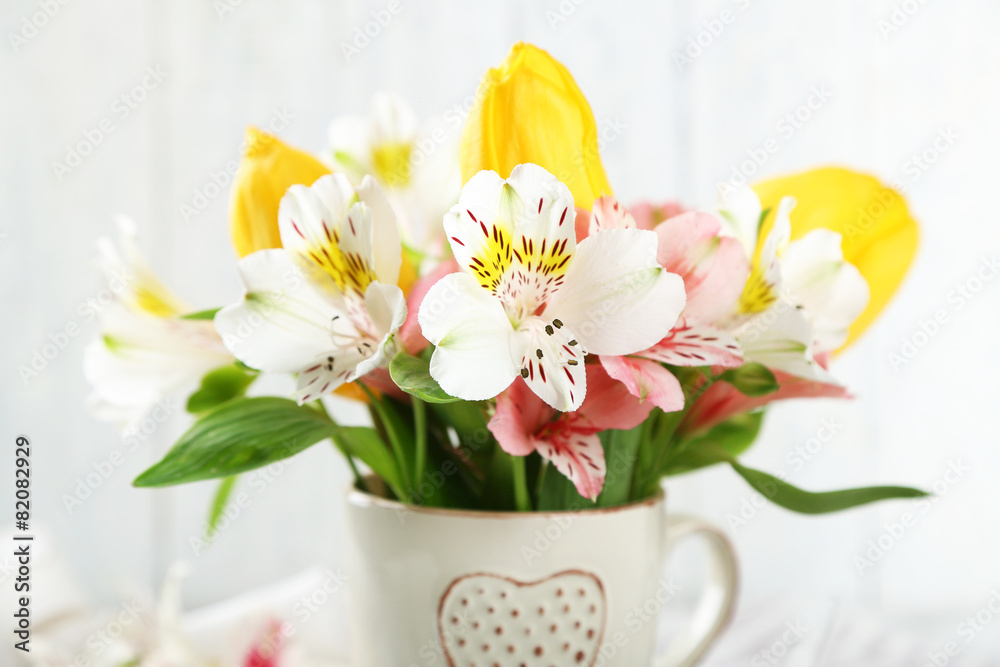 Beautiful flowers in cup, on wooden background Beautiful flowers in cup, on wooden background