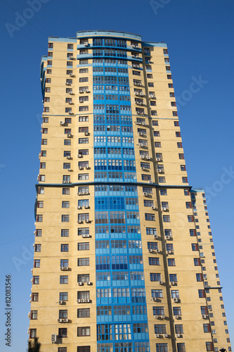 High yellow modern multi-storey building on blue cloudless sky