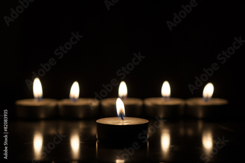 One candle and group of candles on old wooden background