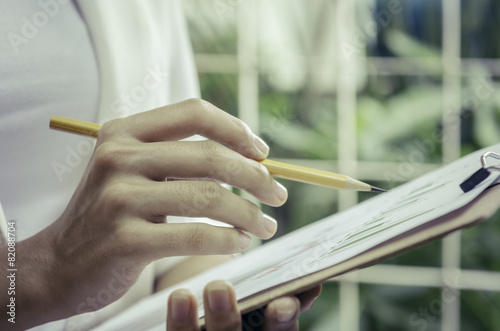 woman’s hands holding a binder while noting