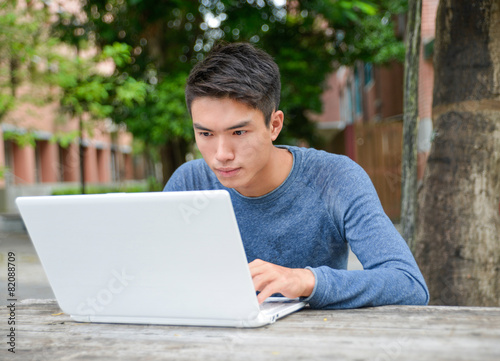 Asian student sitting use laptop in her hand at campus