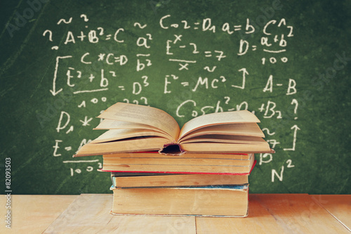  Image of school books on wooden desk over green background with