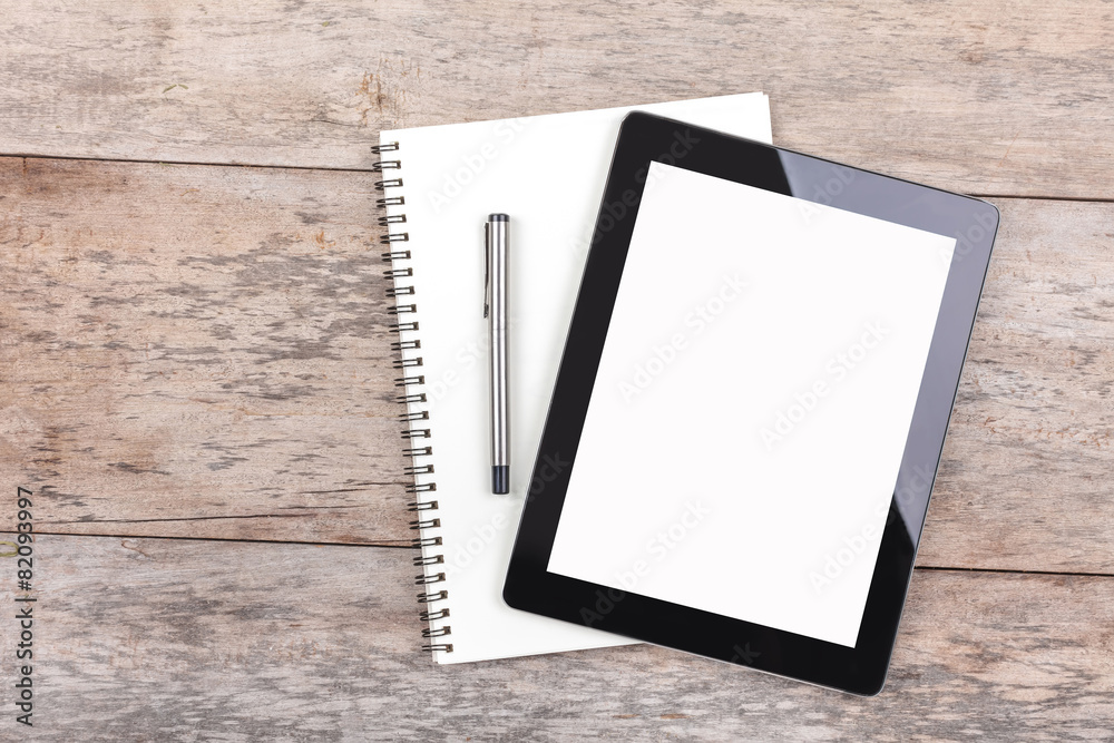 Tablet and notepad on a wooden desktop