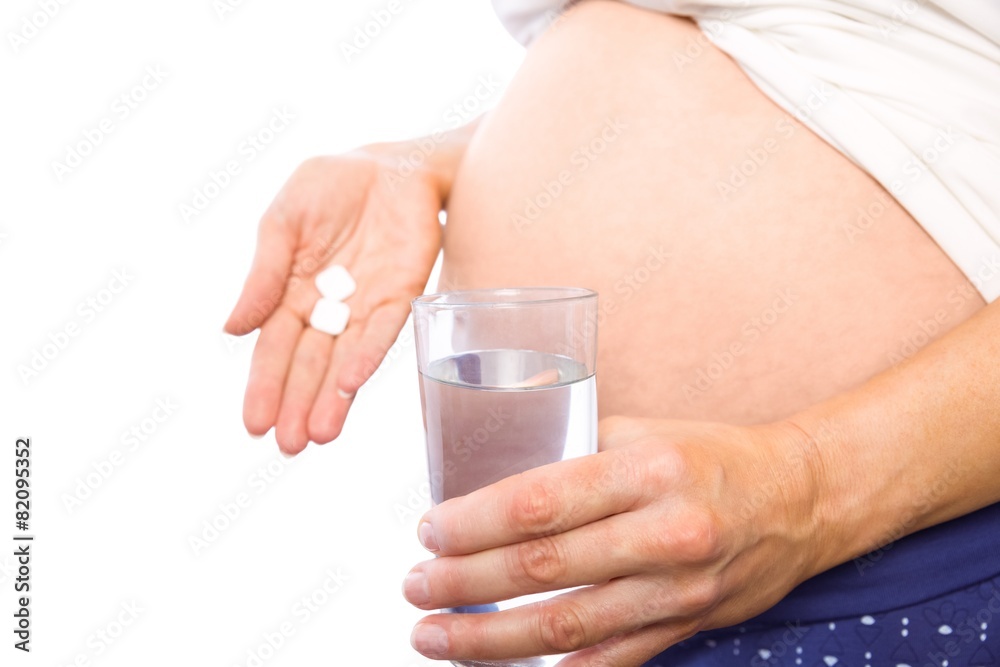 Pregnant woman taking a vitamin tablet