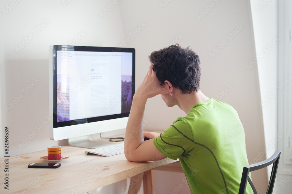 young man looking at the screen of computer at home interior