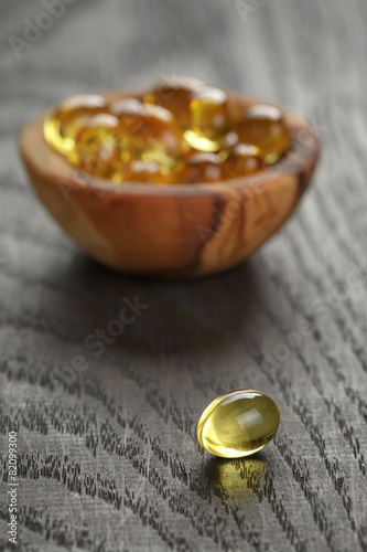 fish oil capsules in wood bowl on wooden table