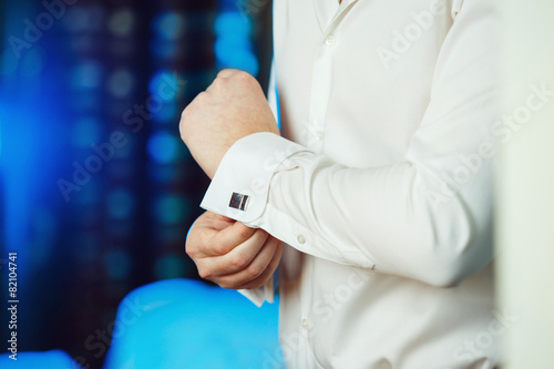 Close-up image of a man who fastens a stud at blue light backgro