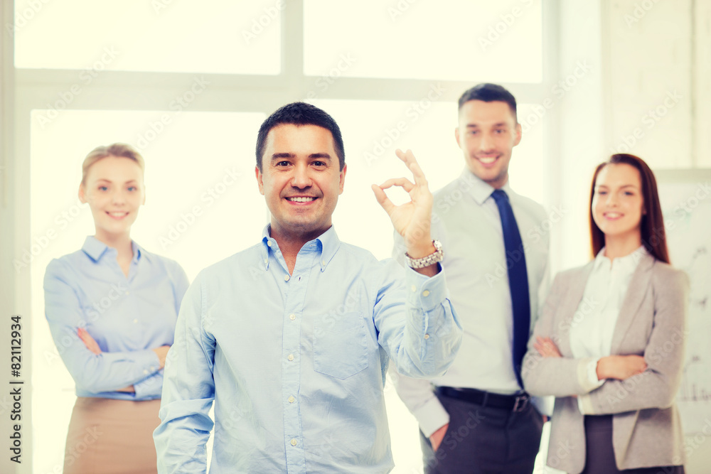 smiling businessman showing ok-sign in office smiling businessman showing ok-sign in office