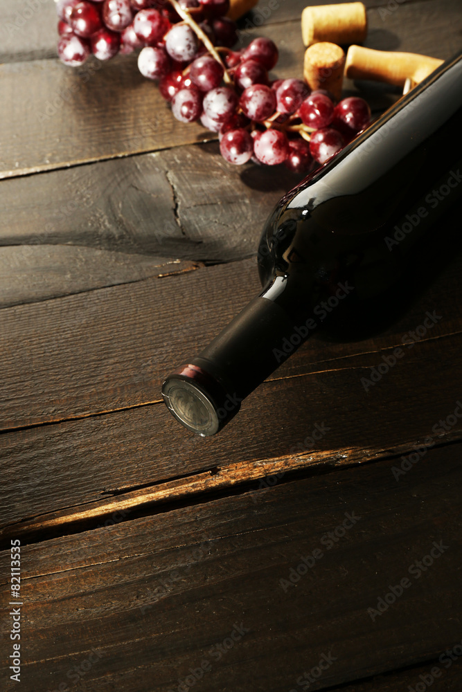 Glass bottle of wine with corks and grapes