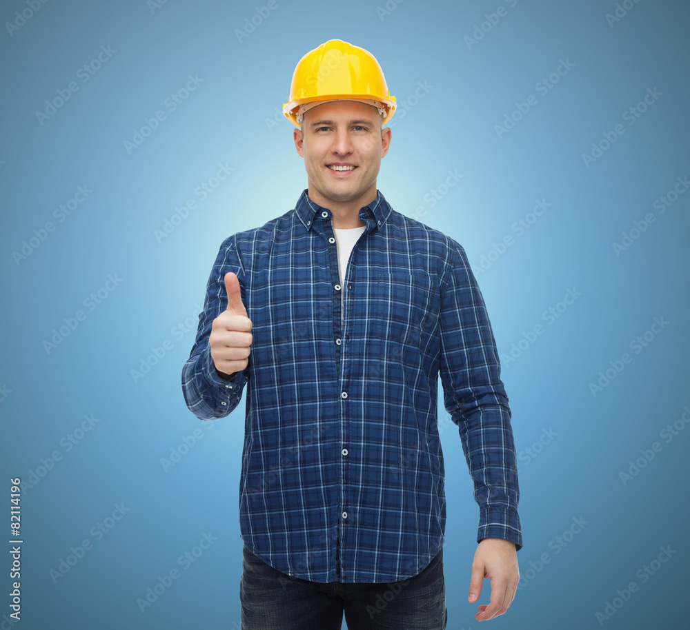 smiling male builder in helmet showing thumbs up