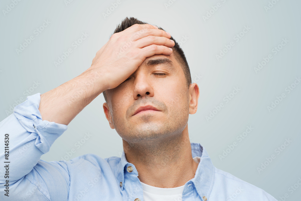 unhappy man with closed eyes touching his forehead unhappy man with closed eyes touching his forehead