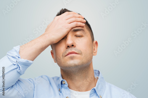 unhappy man with closed eyes touching his forehead photo