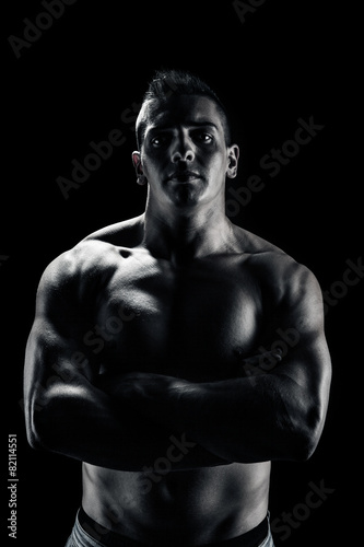 Low light portrait of bodybuilder over black background