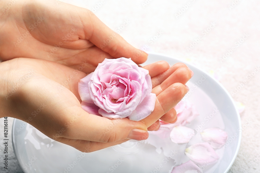 Female hands with bowl of aroma spa water on table, closeup