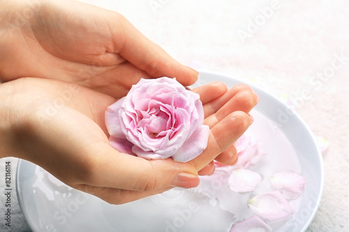 Female hands with bowl of aroma spa water on table, closeup