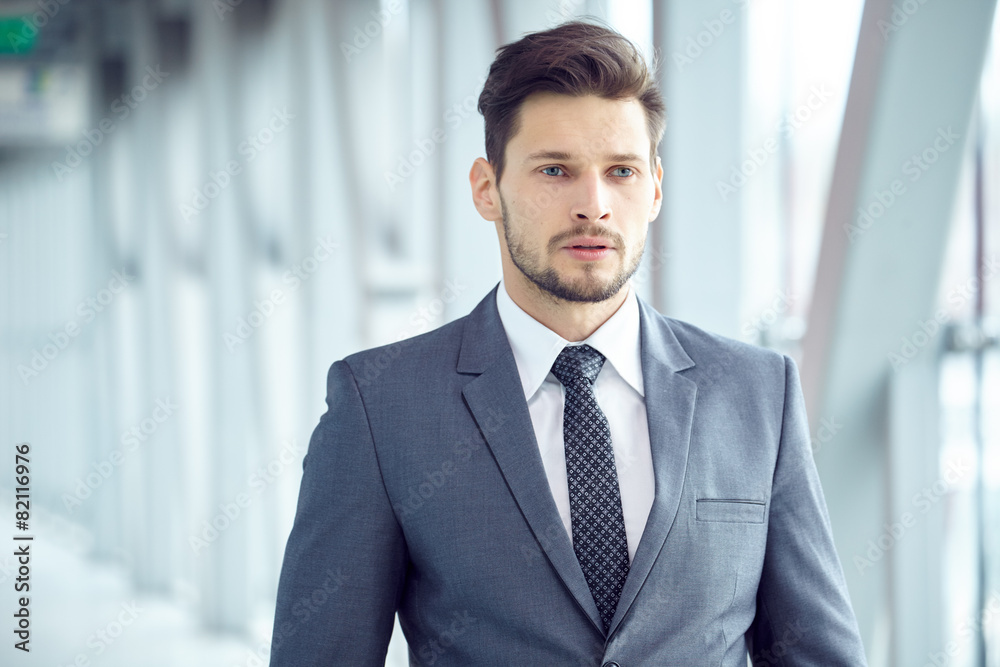 Portrait of a young businessman in suit standing at office Portrait of a young businessman in suit standing at office