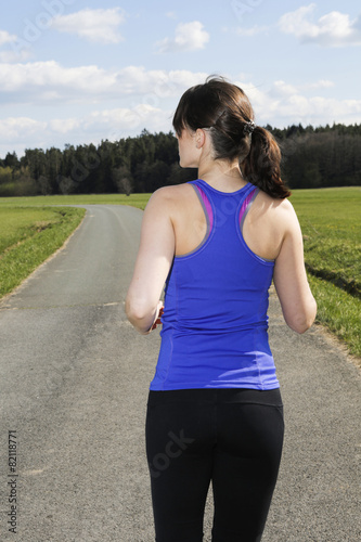 backside of a young woman jogging outdoors