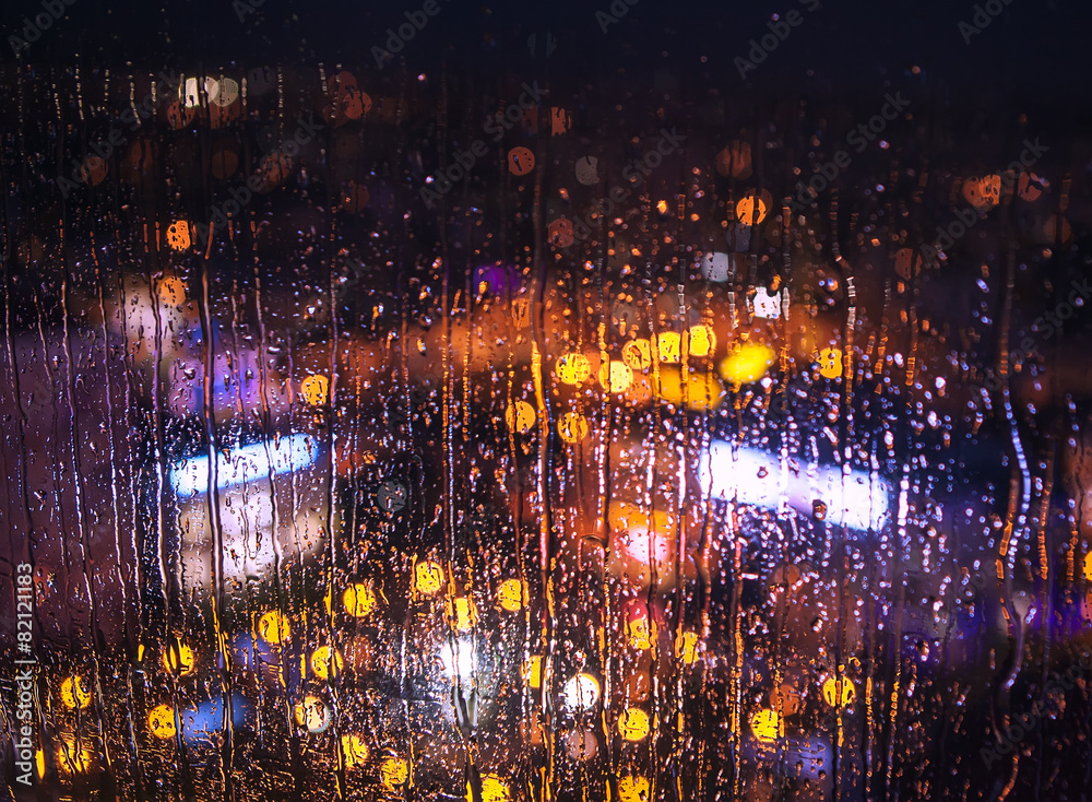 Night city lights behind rainy window