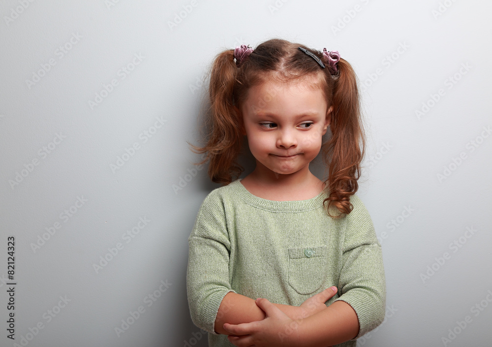Fun thinking kid girl looking on blue wall background Fun thinking kid girl looking on blue wall background
