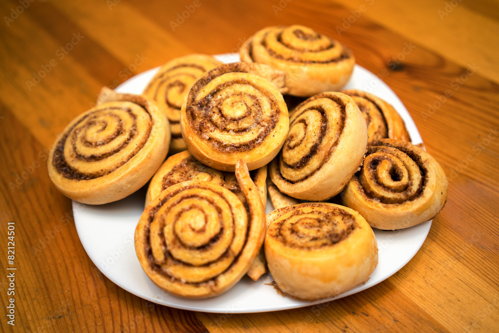 cinnamon rolls on a white dish in a wooden table cinnamon rolls on a white dish in a wooden table
