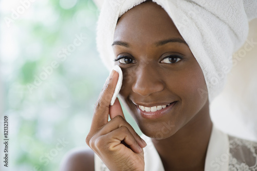 Black woman wiping face with cotton pad
