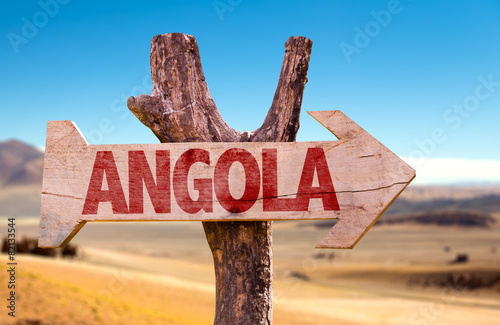 Angola wooden sign with desertic road background photo