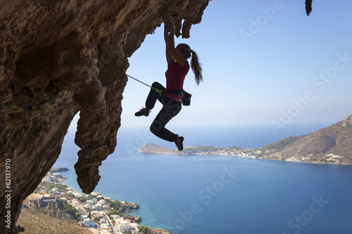 Female rock climber struggling on challenging route on cliff  photo