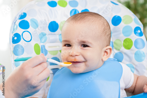 Adorable smiling cute baby eating mash