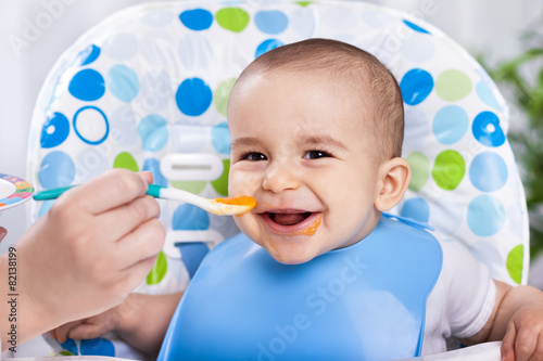 Smiling happy adorable baby eating fruit mash