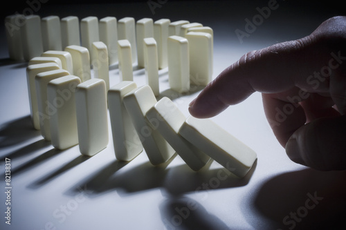 Hispanic man knocking over dominoes