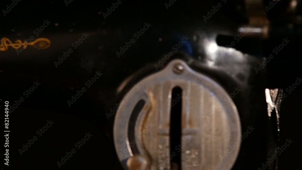 Woman`s hand using an old sewing machine on black background Woman`s hand using an old sewing machine on black background
