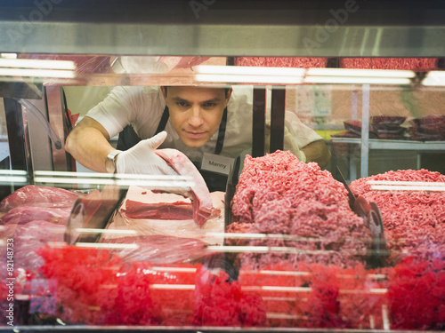 Hispanic butcher at meat counter of grocery store