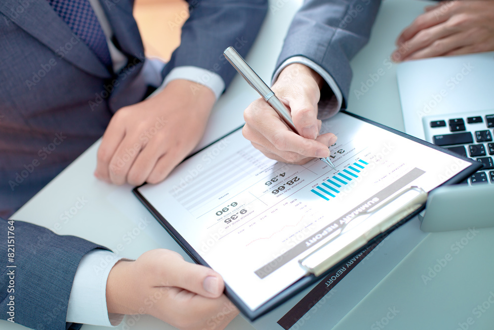 Two businessmen looking at report and having a discussion in off Two businessmen looking at report and having a discussion in off