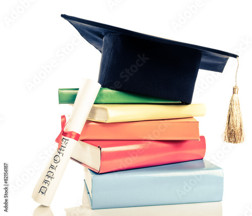 A mortarboard and graduation scroll, tied with red ribbon, on a photo