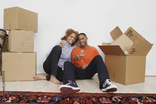 African couple with wine next to moving boxes photo