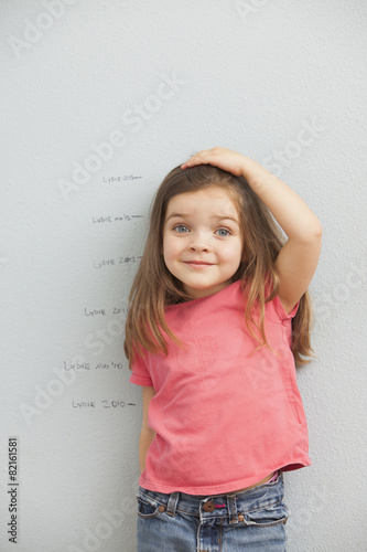 Caucasian girl measuring her height on wall