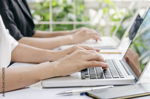 two business workers typing data in laptop