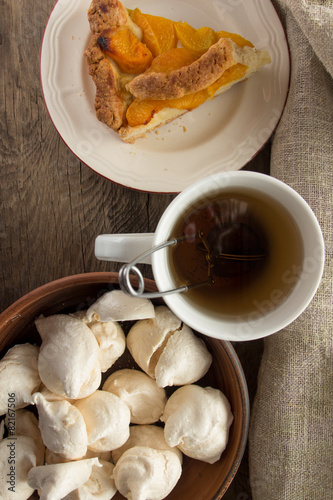 Shortcrust peach pie, meringues and cup of tea