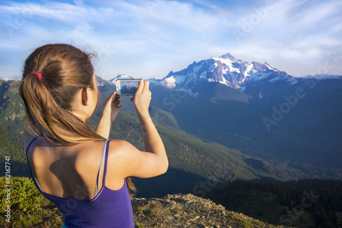Mixed race girl photographing mountains, North Cascade Mountains, Washington, United States