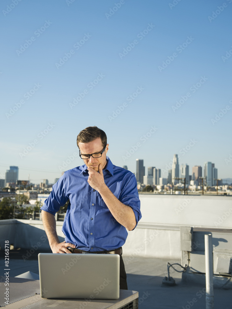 Caucasian businessman using laptop on urban rooftop Caucasian businessman using laptop on urban rooftop