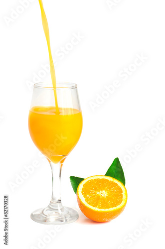 orange juice pouring into glass with orange slice and leaf, isol