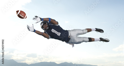 African American football player catching ball